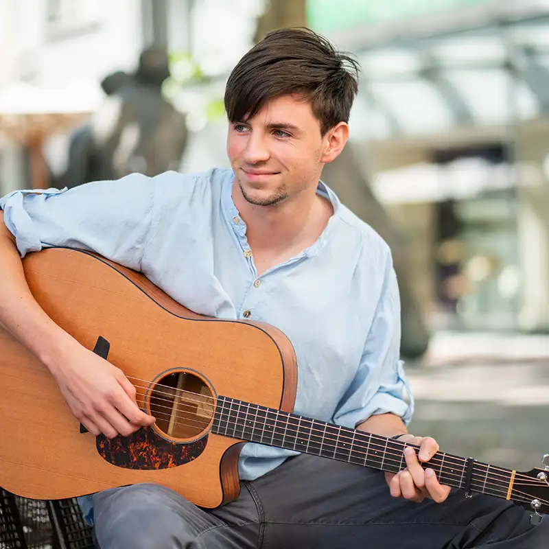 Junger Mann mit schönen Haaren spielt Gitarre